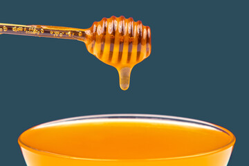 Naklejka premium fresh fragrant honey drips from a spoon into a plate on a colored background. organic vitamin nutrition. dessert food