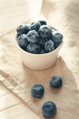 Freshly picked juicy blueberries in the bowl on wooden background, close up. Blueberries background. Concept of healthy nutrition, organic food. Vegan and vegetarian