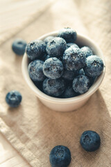 Freshly picked juicy blueberries in the bowl on wooden background, close up. Blueberries background. Concept of healthy nutrition, organic food. Vegan and vegetarian