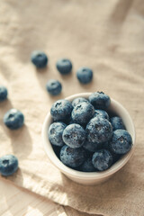 Freshly picked juicy blueberries in the bowl on wooden background, close up. Blueberries background. Concept of healthy nutrition, organic food. Vegan and vegetarian