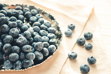 Freshly picked juicy blueberries in the bowl on wooden background, close up. Blueberries background. Concept of healthy nutrition, organic food. Vegan and vegetarian