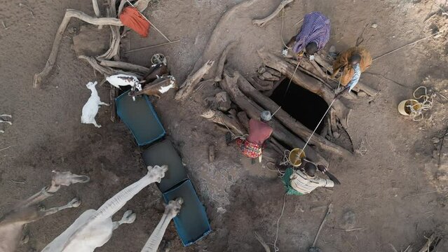 Climate change.drought.water crisis.Straight down aerial view.African men drawing water for livestock,goats,camels from very deep wells due to persistent drought. Kenya