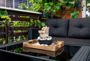 Home patio with black plastic garden furniture, small relaxing electrical zen table fountain on...