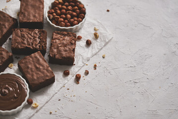Delicious homemade chocolate brownie served with hazelnuts and melted cream