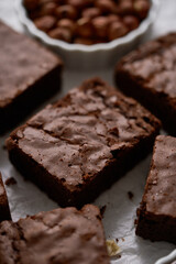 Fresh homemade chocolate brownie served with hazelnuts and melted cream