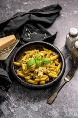Pasta with parmesan cheese and creamy pesto sauce in black bowl