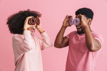 Black man and woman smiling and having fun with donuts