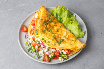 Homemade stuffed omelet on a plate. Egg omelet stuffed with fresh tomatoes, cheese and green parsley. Healthy vegetarian breakfast recipe.