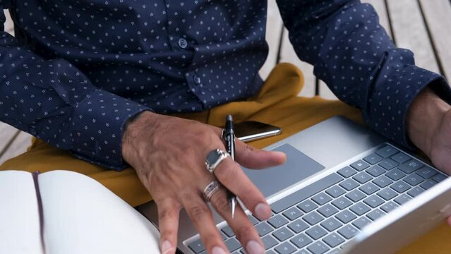 CU Stylish man using laptop and writing in notebook outdoors / London, UK