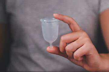 Hand holding menstrual cup. Studio picture of modern sanitary products for period. Women health, gynecology, hygiene, zero waste alternatives concept. Eco-friendly silicone menstrual cup for women.