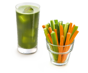 Copo com suco verde com gelo e pote com palitos de pepino e cenoura 