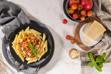 Tasty appetizing classic italian penne pasta with vegetarian lentil bolognese sauce, cheese parmesan and basil on plate on light table. Healthy eating concept.
