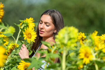 sensual slim woman with long hair in a sunflower field on a sunny summer day