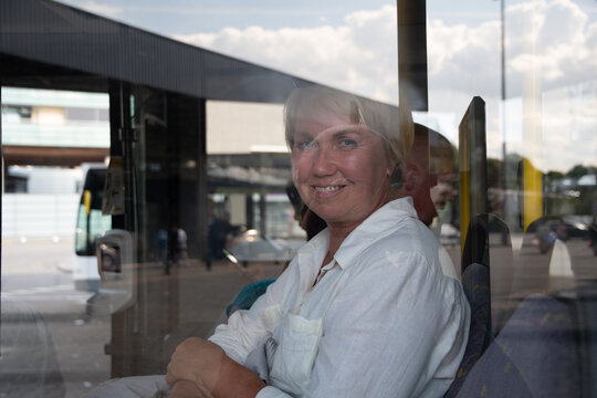 middleaged caucasian woman sitting in bus pictures through glass with reflection