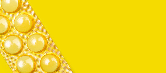 Blister de pastillas mediamentos amarillas sobre fondo amarillo brillante liso y aisado. Vista superior y de cerca. Copy space. Concepto: Banner de salud © Mercedes Fittipaldi