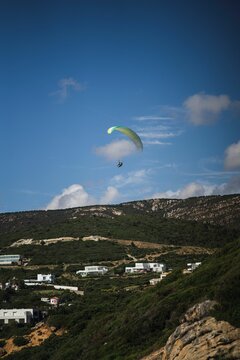 Beautiful Scenery Of A Human Parachuting In The Mountains Above White Buildings