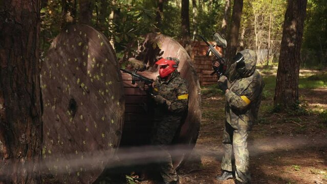 Participating in leisure activities, engaging in outdoor paintball games with friends wearing camouflage, protective masks, taking part in leisure activities, adrenaline sport