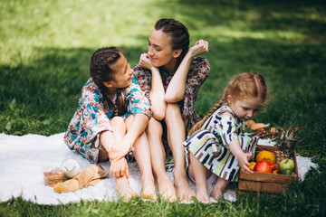 Mother with daughters having picnic in park 