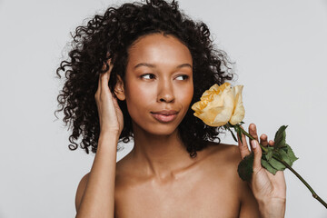 Shirtless black woman laughing while posing with rose