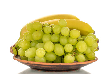 One bunch of white grapes Quiche mish and bananas on a ceramic plate, close-up, isolated on a white background.