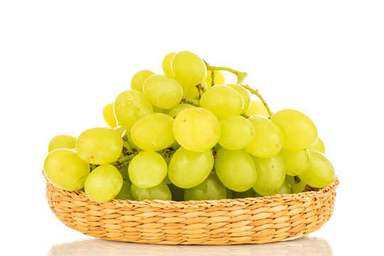 One bunch of white grapes in a straw bowl, close-up, isolated on a white background.