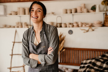 Young beautiful smiling woman in apron with folded arms