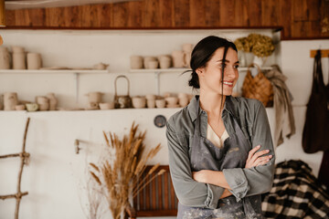 Young beautiful smiling woman in apron with folded arms