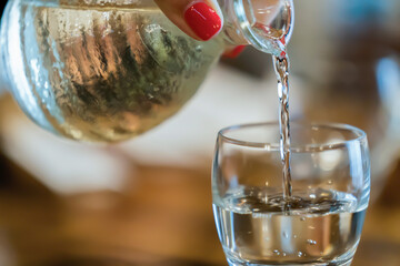 The glass water bottle and glass being poured