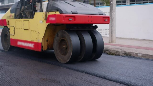 Fresh asphalt road with workers and paving machines, road construction process