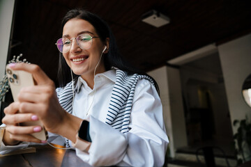 White woman listening music with gadgets while sitting at cafe