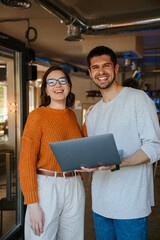 White colleagues discussing project while working with laptop in office