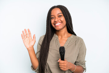 black pretty woman smiling happily, waving hand, welcoming and greeting you. singer with a...