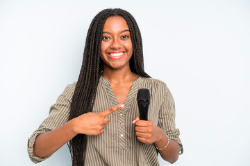 black pretty woman smiling cheerfully, feeling happy and pointing to the side. singer with a...