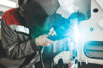 Body shop worker welding car body. Work with carbon dioxide weld.