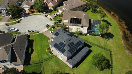 Bird's eye view of houses with solar panels on rooftops in a green residential district