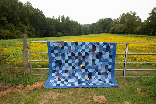 blue patchwork quilt on fence with meadow 2