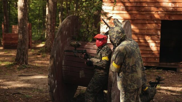 The thrill of playing paintball with friends while wearing camouflage and protective masks, an adrenaline-packed sport, outdoor paintball, taking part in leisure activities.