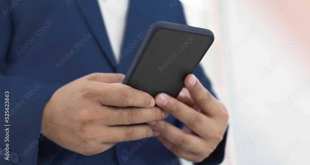 Poster close up image of businessman holding and using smart phone with selective focus