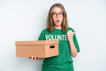 caucasian pretty woman looking excited and surprised pointing to the side. volunteer and donation...