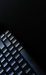 Black mechanical keyboard on a black desk vertical background