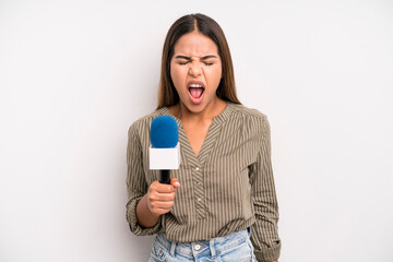 hispanic pretty woman shouting aggressively, looking very angry. presenter with a microphone concept