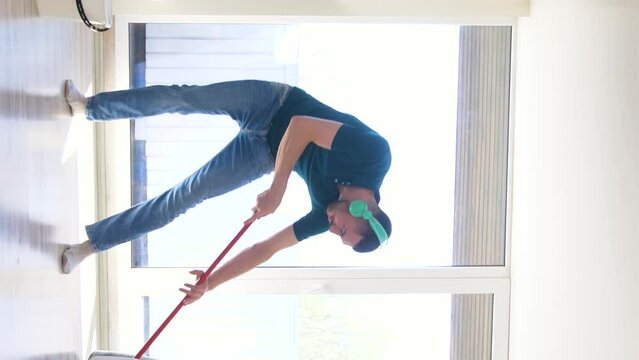 people, housework and housekeeping concept - happy man in headphones with mop cleaning floor and dancing at home, vertical view orientation