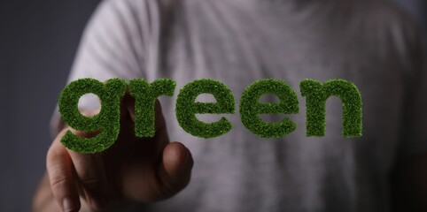 Man's hand touching a sign saying green in a grass design - concept of green movement