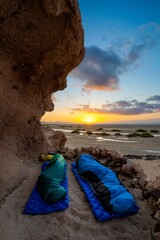 Vertikale Aufnahme von zwei Wanderern, die in Schlafsäcken am Strand Laguna de Sotavento auf Fuerteventura schlafen
