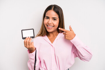 hispanic pretty woman smiling confidently pointing to own broad smile. pass id card concept