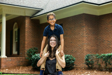 A big sister holding her little brother on her shoulders for a fun portrait