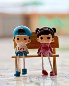 Vertical Closeup Shot Of Two Small Figures Of Girl And Boy Sitting On The Bench