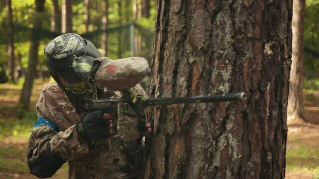 Participating in a leisure activity, playing paintball with friends wearing camouflage, protective masks, an action and adrenaline sport, an outdoor paintball game