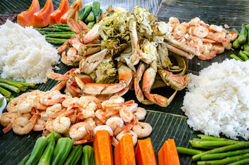 Boodle fight is a social, social meal or buffet eaten using hands seen here including crab, prawns, okra, asparagus and boiled rice.