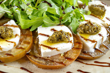 Caprese salad. Tomatoes, mozzarella cheese, basil leaves and pesto sauce.